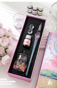 Detailed gift box set with gradient glass dip pen, ink, holder, and floral cup on a desk