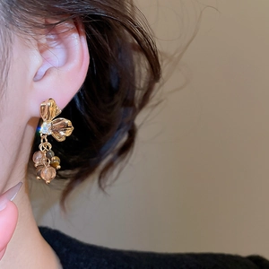 Detail of flower-shaped golden earrings with dangling beads worn by a model