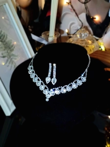 Luxurious silver V-shaped necklace and drop earrings set on a velvet display
