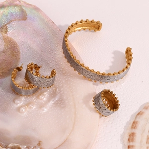 Detail of two-tone jewelry set featuring textured gold and silver finish with beaded edges