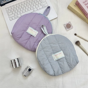 Flat lay of purple and blue quilted shell cosmetic bags with travel accessories