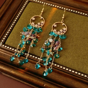 Close-up of vintage gold tassel earrings with zircon stars on dark velvet surface
