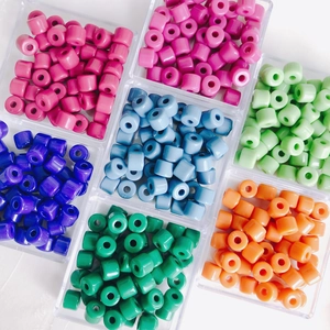 Macro view of colorful acrylic cylinder beads organized by color in a plastic tray