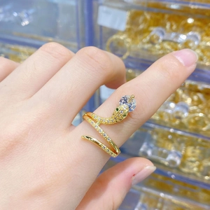 Detailed view of a golden snake ring with zircon stones on a person's finger