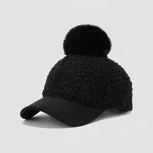 Detail of kids black fleece baseball cap with large faux fur pom-pom and sleek flat brim