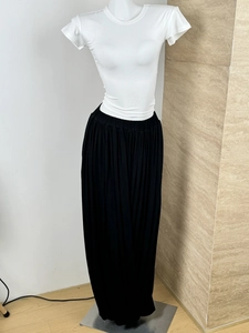 Detail of high-waist black pleated wide-leg trousers with elastic waistband
