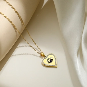 Golden heart necklace with evil eye pendant and blue gemstone on silk background