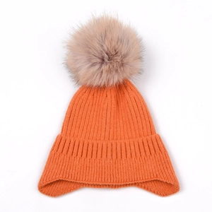 Orange knit earflap beanie with fluffy brown faux fur pom pom on plain white background