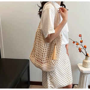 Close-up of beige hollow knit tote bag featuring large mesh design and stylish tassel