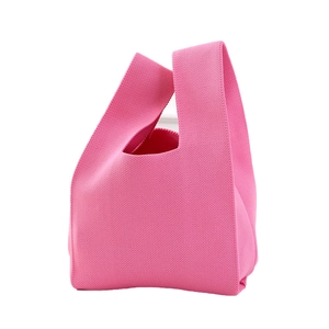 Minimalist bright pink knitted handbag with dense weave texture on white background
