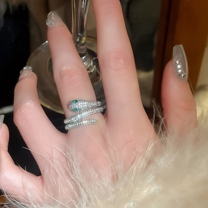 Detailed view of silver snake ring with green stone eyes and pave zircon on female hand