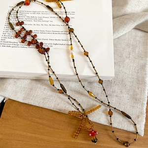 Detail of vintage beaded necklace with handmade bow and red mushroom pendant charm
