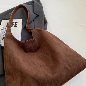 Detail of dark brown suede tote bag featuring a semi-moon shape and smooth leather strap