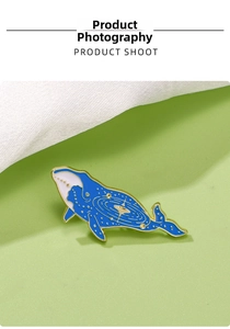 Macro shot of blue whale enamel pin with golden galaxy swirls and starry details