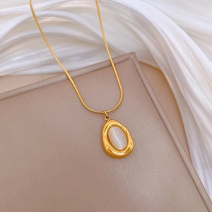 Detailed close-up of golden irregular water drop necklace with white cat eye stone