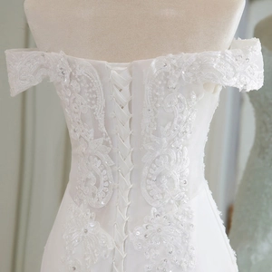Detail of white lace wedding dress featuring corset back ties and off-shoulder floral lace