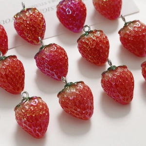 Macro shot of realistic resin strawberry pendants with green leaves and metal rings