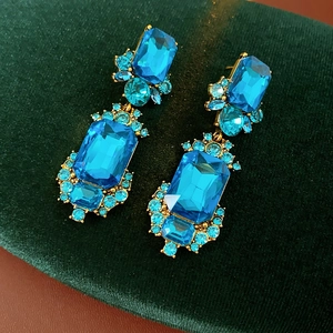 Detail of vintage gold earrings with blue gemstones on dark green velvet background
