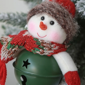 Macro view of snowman Christmas ornament with green metal bell and knit scarf details