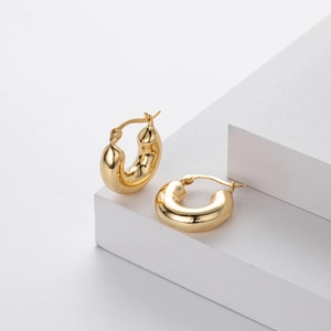 Macro shot of thick gold hoops showing S925 hallmark on minimalist silver earrings