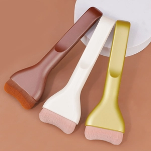 Three professional flat tongue foundation brushes with ultra-thin bristles on a warm background
