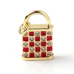 Macro shot of gold-plated lock pendant featuring red checkerboard enamel and crystal inlay