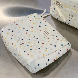Close-up of white quilted cotton makeup bag with colorful polka dots and silver zipper