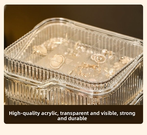 Close-up of a clear acrylic jewelry box featuring a dustproof lid and multi-grid storage