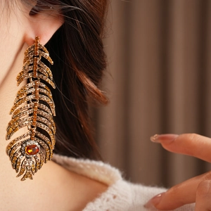 Detail of vintage feather earrings with amber crystals and bronze finish on model