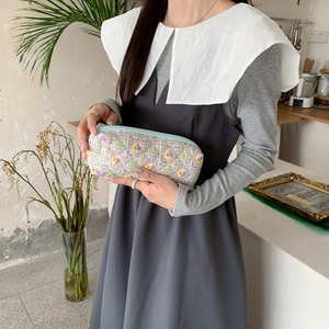 Detailed view of a large capacity floral fabric pencil case and makeup pouch held by model