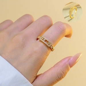 Close-up of a wide gold-plated ring with moving zircon stones and hollow rectangular design