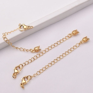 Detailed macro of gold-plated jewelry extender chains with lobster clasps and leaf charms