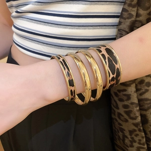 Close-up of four-piece gold leopard print bracelets set worn on a model's wrist