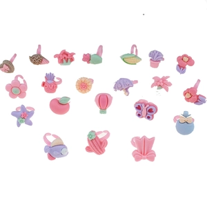 Flat lay of 20 assorted colorful plastic children rings with cute flowers and fruit shapes