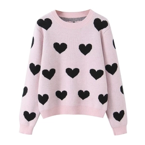 Pink long-sleeve knit sweater with all-over black heart jacquard pattern on white background