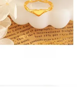 Detail of a minimalist gold heart ring with wave chain design on white decorative stand