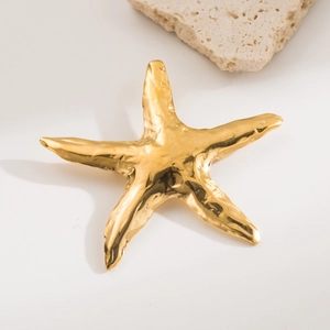 Elegant gold starfish brooch in stainless steel with textured finish on a white surface