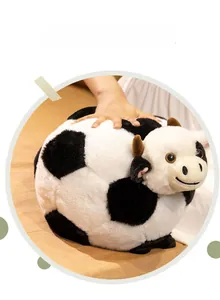Close-up of a round soccer cow plush toy with soft black and white fur and cute horns