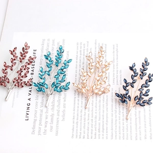 Macro detail of leaf-shaped crystal brooches in pink, blue, and gold on a magazine