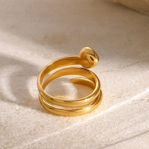 Close-up of polished gold-plated wrap ring with waterdrop detail on stone background