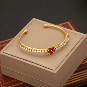 Detail of gold floral bangle with red flower and zircon inlay on a jewelry box