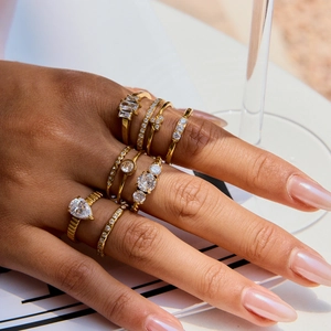 Close-up of a gold-plated ring set with white cubic zirconia worn by a model in sunlight