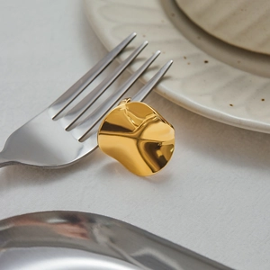 Macro shot of an irregular gold wavy ring on a silver fork in a dining setting
