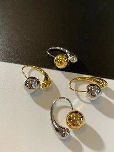 Macro detail of two-tone metal teardrop earrings with polished spheres in gold and silver