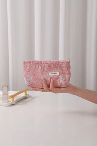 Close-up of pink linen makeup bag featuring white floral embroidery and zipper detail