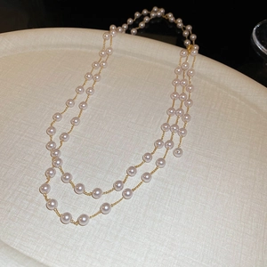Détail macro d'un collier de perles artificielles double couche avec chaînes dorées