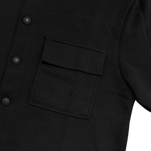 Close-up of black twill jacket featuring a chest flap pocket and matte buttons detail