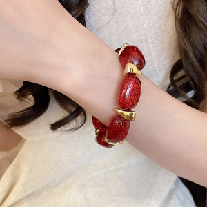 Close-up of red acrylic oval beads bracelet with gold-toned spacers on a wrist