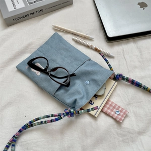 Close-up of light blue corduroy bag featuring rabbit embroidery and woven rope strap