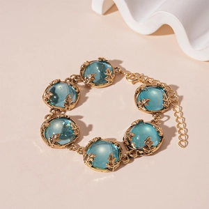 Close-up of vintage golden bracelet with blue resin stones and intricate leaf claws